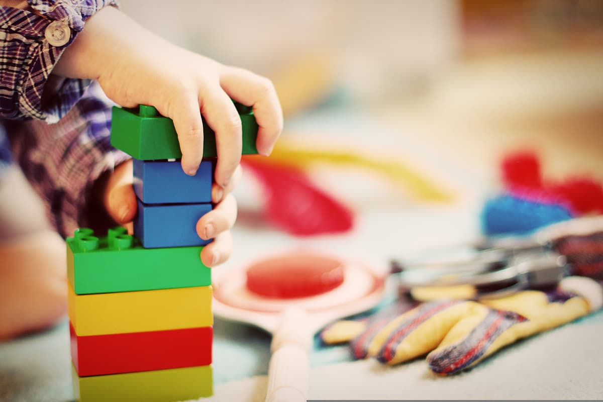 Bambino che impila mattoncini colorati in legno per creare una torre